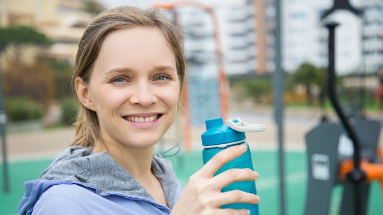 Femme buvant de l'eau hydrogénée depuis une gourde, symbole de santé et bien-être